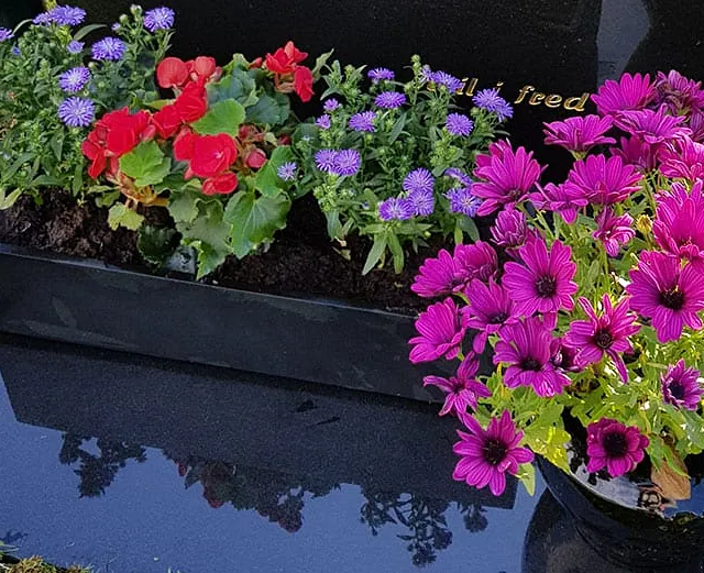 Blomsterbuketter foran gravstøtte